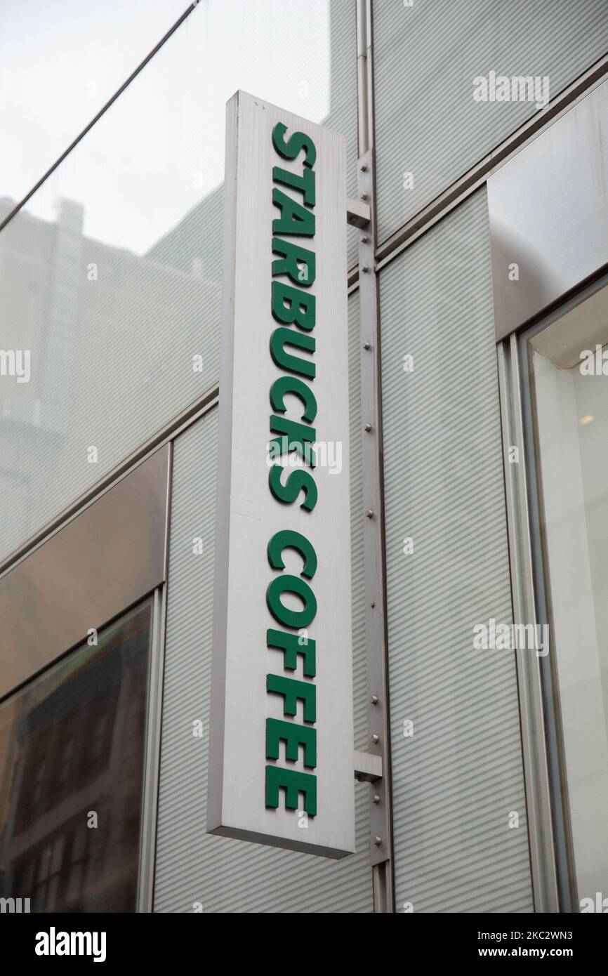 Inscription logo at a store front of a Starbucks Coffee shop located in Midtown Manhattan with people walking by. Starbucks Corporation is the world's largest coffeehouse chain, an American multinational cafe chain with headquarters in Seattle Washington. NYC, United States of America on February 2020 (Photo by Nicolas Economou/NurPhoto) Stock Photo