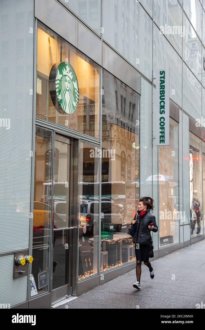 A woman running in rush next to a store front of a Starbucks Coffee