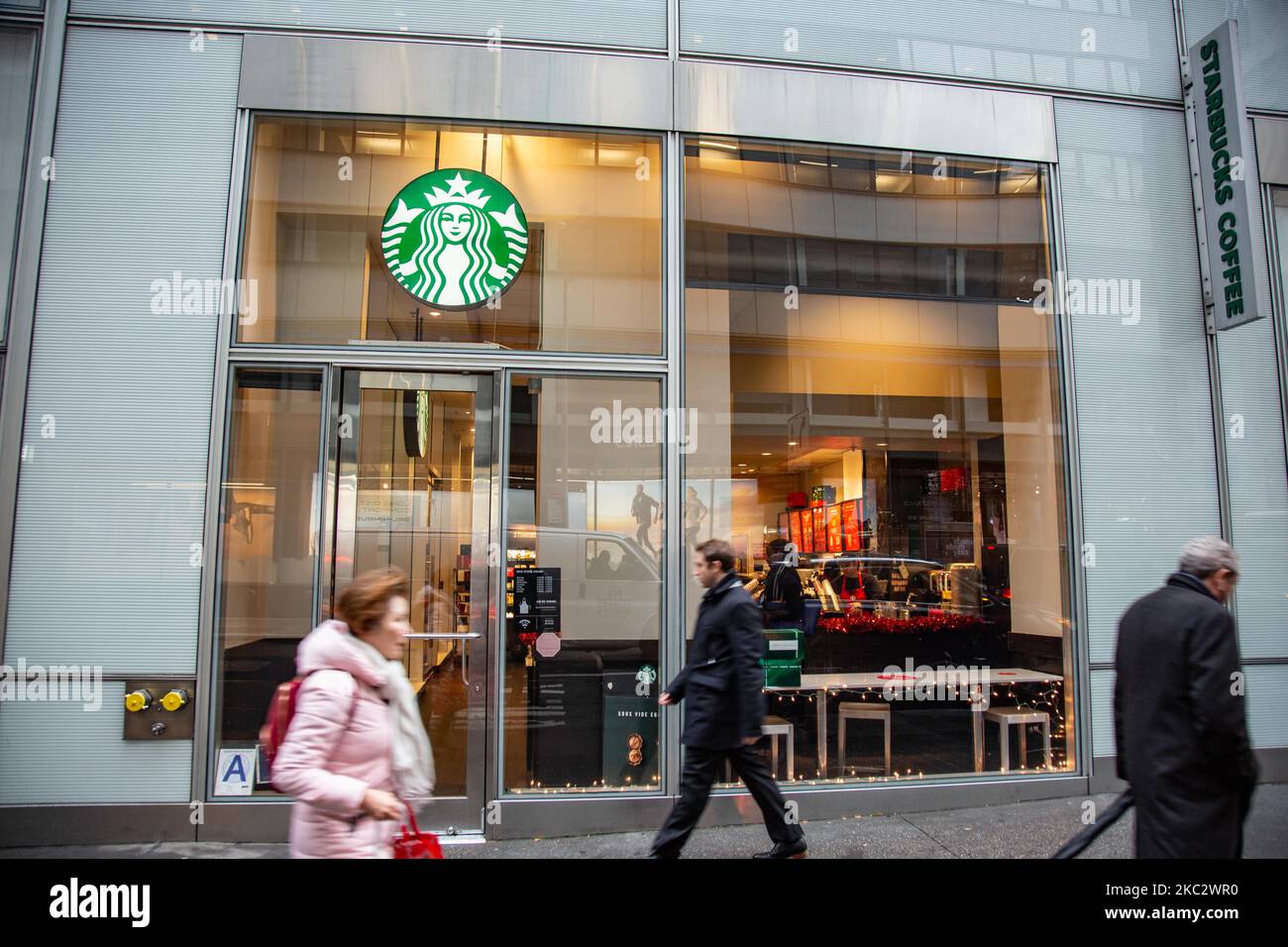 A store front of a Starbucks Coffee shop located in Midtown Manhattan with people walking by. Starbucks Corporation is the world's largest coffeehouse chain, an American multinational cafe chain with headquarters in Seattle Washington. NYC, United States of America on February 2020 (Photo by Nicolas Economou/NurPhoto) Stock Photo