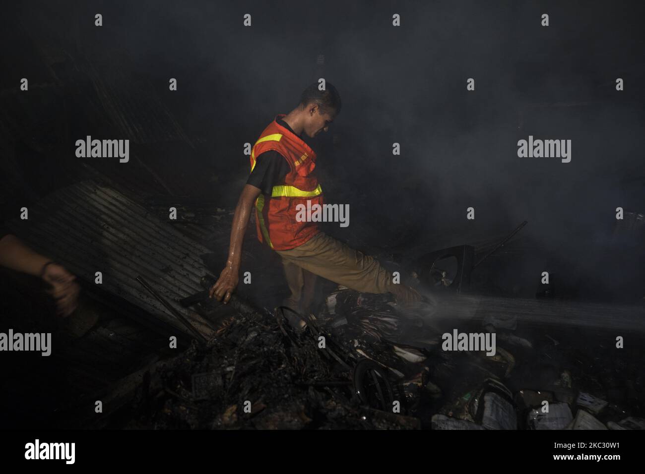 A volunteer work to extinguish a fire that broke out in a slum in Dhaka ...