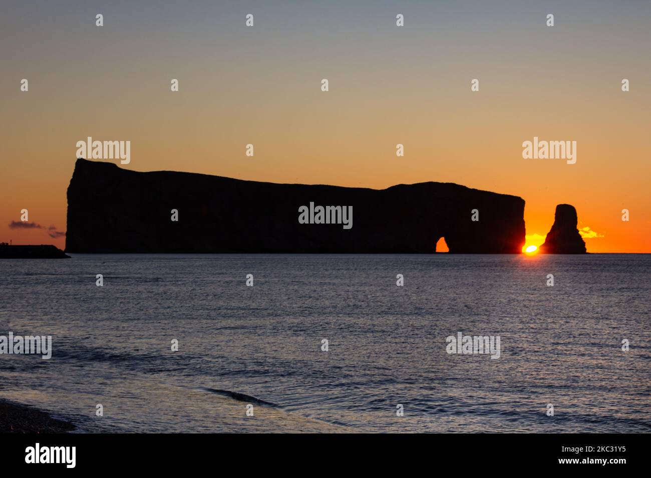 Sunrise on Rocher Perce rock in Gaspe Peninsula, Quebec, Gaspesie region, Canada. Famous landmark in St-Lawrence gulf water. Stock Photo