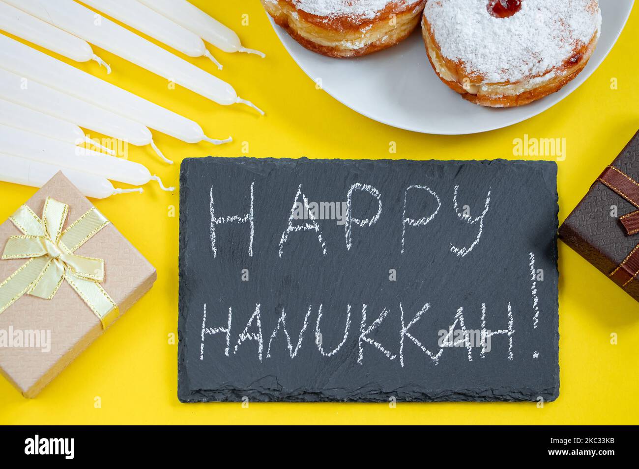 Happy Hanukkah. Jewish dessert Sufganiyot on yellow background. Symbols