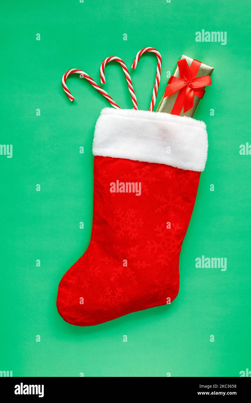 Christmas stocking with small gift box and candy canes on green ...