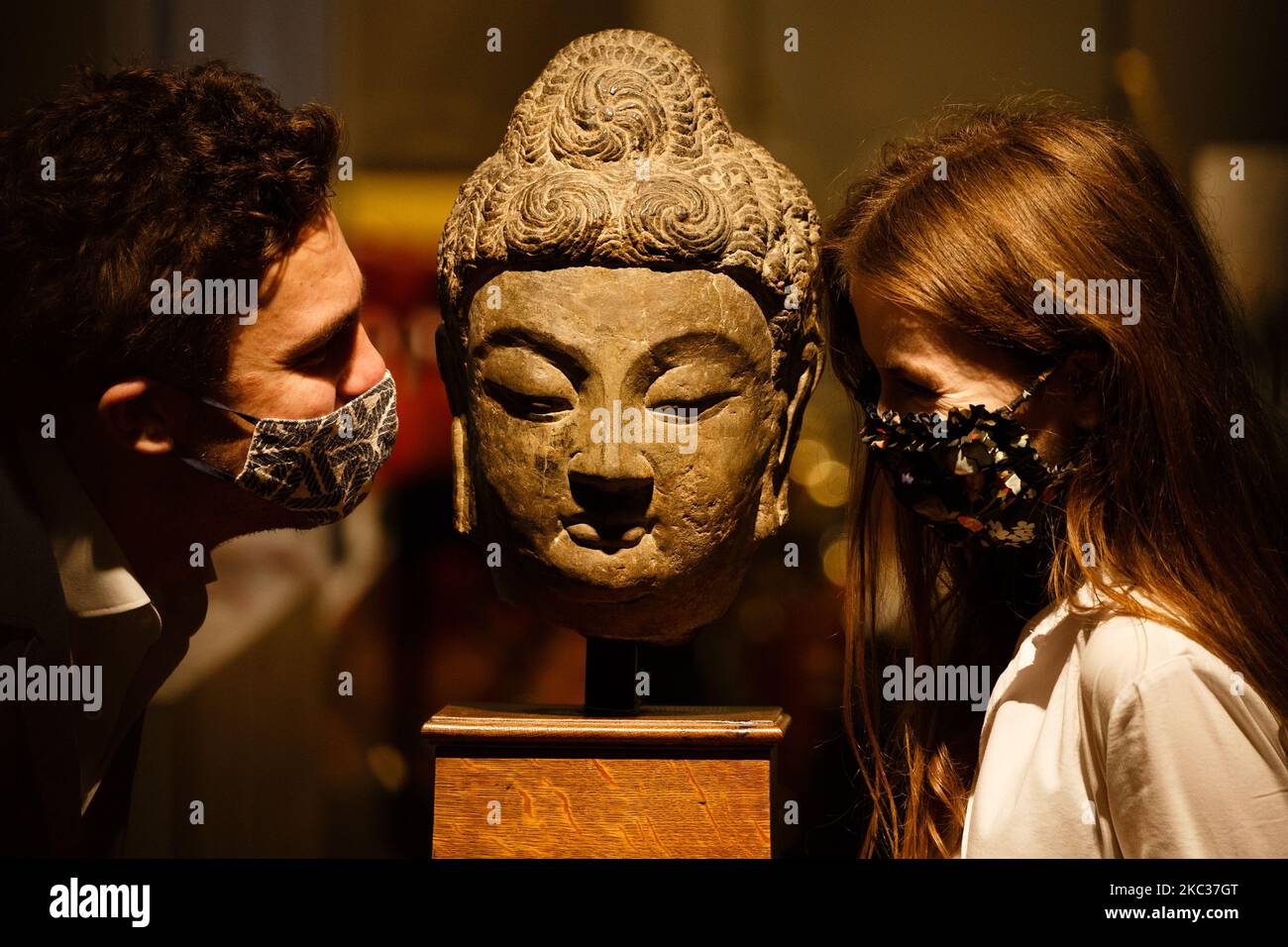 Members of staff poses with a grey limestone Buddha head from the 7th