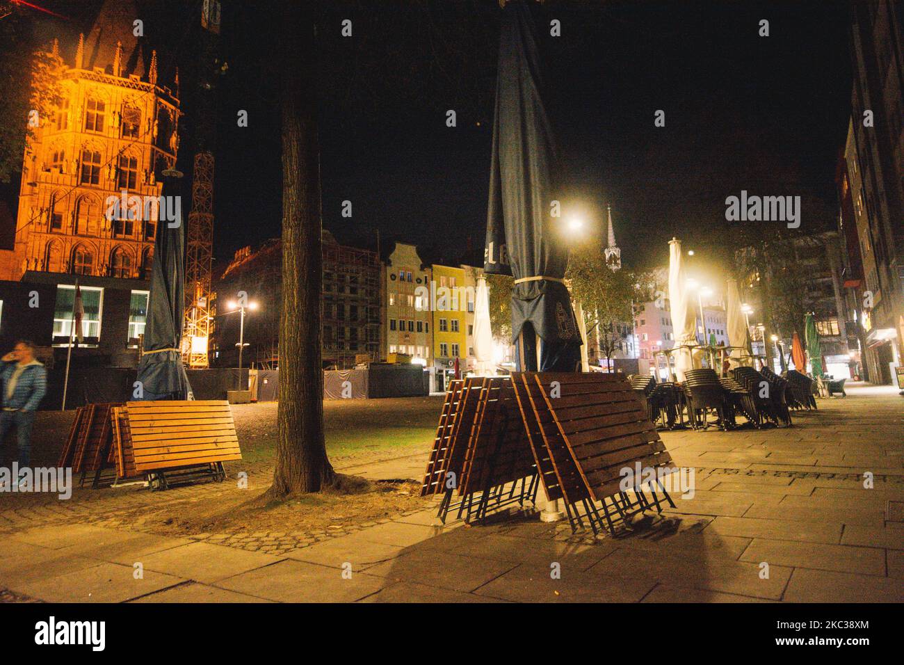 Empty chairs and tables are seen in front of dom cathedral at night