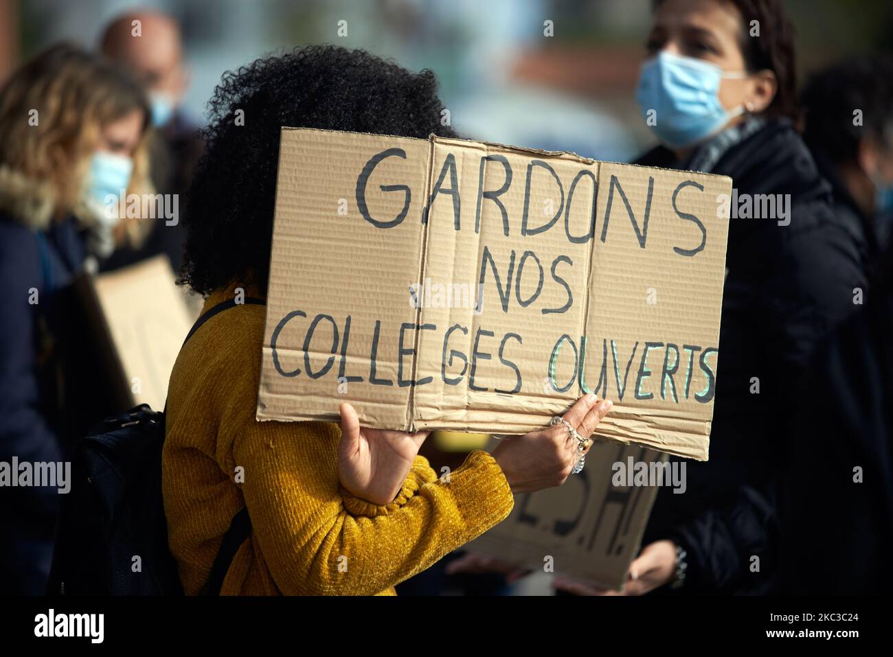 A teacher holds a cardboard reading 'Let's us keep our highschools open'. Teachers gathered in front of the Local Education Authority of Toulouse as they protest for their duty to protect pupils from the Covid-19 illness with Education minister sanitary protocols such as social distanciation and protectives measures. They say it's impossible to respect the measures as they must do the classroom with all pupls present. They ask to give courses by half class, one in the morning, one in the afternoon. Toulouse. France. November 5th 2020. (Photo by Alain Pitton/NurPhoto) Stock Photo