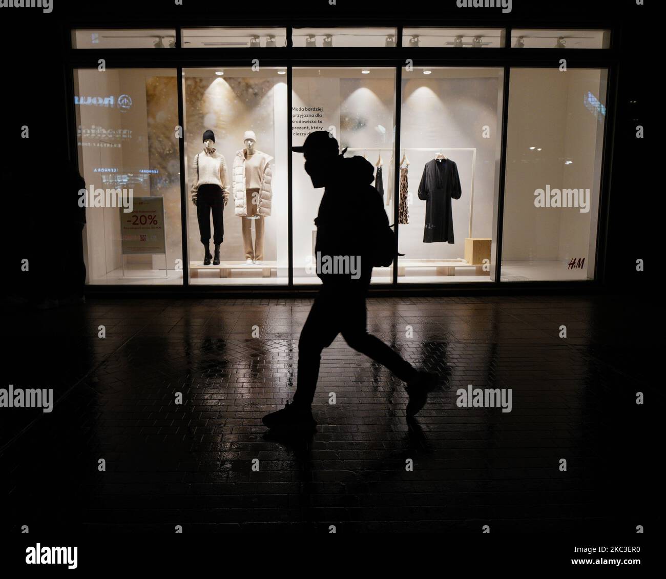 People walk past a shopping window display with mannequins in Warsaw, Poland on November 6, 2020. A partial lockdown will be imposed for two weeks starting on Saturday across the entire country. Daily cases of coronavirus infections have kept rising in the last two weeks despite restaurants and bars having been closed in addition to implementing distance learning for most grades in schools. To prevent a collapse of the overburdened healthcare system the Prime Minister's office announced new restrictions including the closing of shopping malls, hotels for tourists and mandatory distance learnin Stock Photo