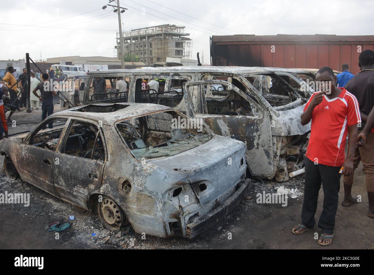 People stand next to burned cars after a tanker exploded on Lagos
