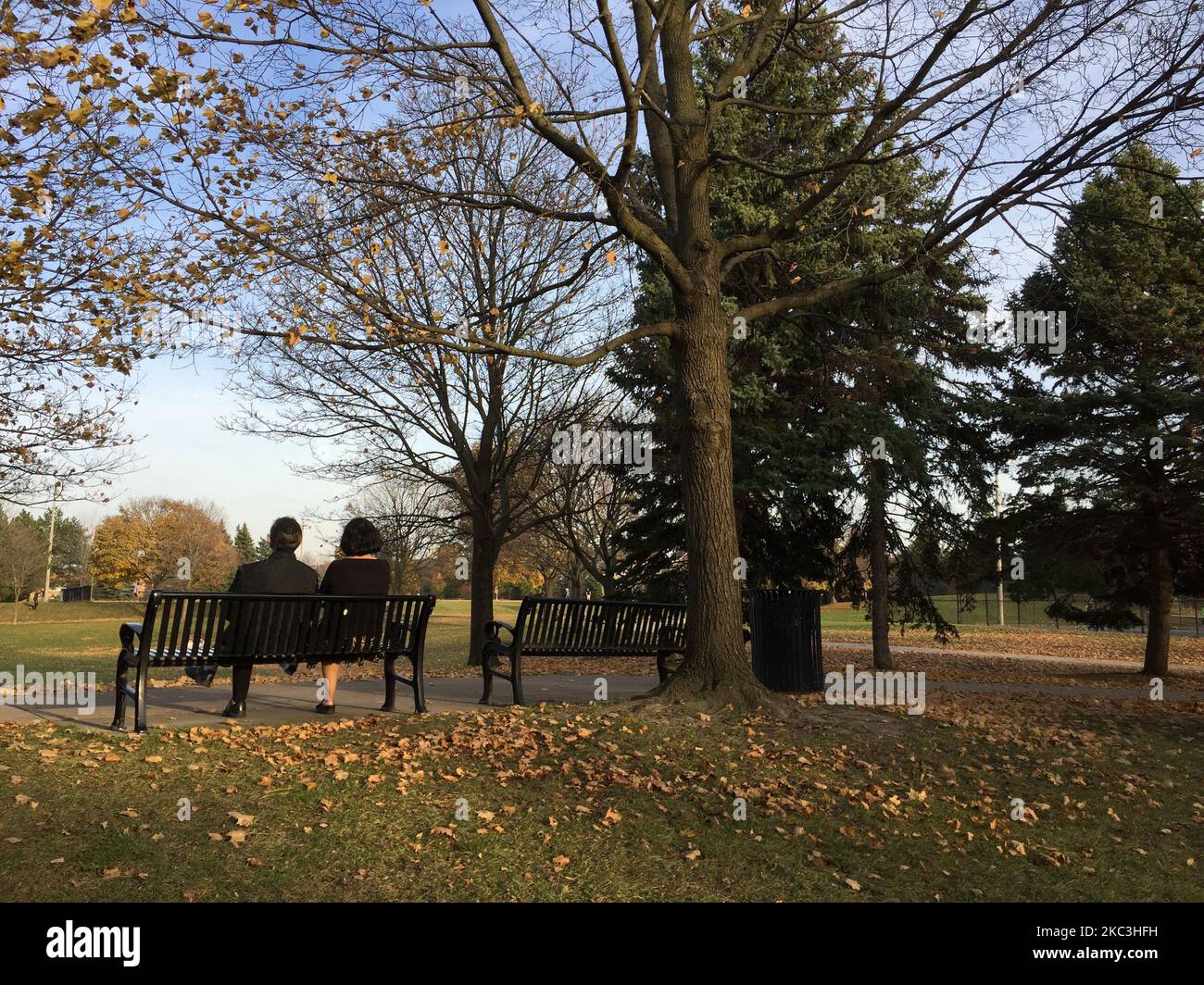 Couple sitting on a bench at a park in Toronto, Ontario, Canada, on November 07, 2020. Toronto is experiencing the warmest stretch of November weather in history with temperatures hitting a high of 20 degrees celsius. Friday's high of 20.8 °C broke the record of 20.5 °C set in 2015 and Sunday temperatures in Toronto are expected to reach 20°C. This trend will continue into the early days of next week as well. (Photo by Creative Touch Imaging Ltd./NurPhoto) Stock Photo