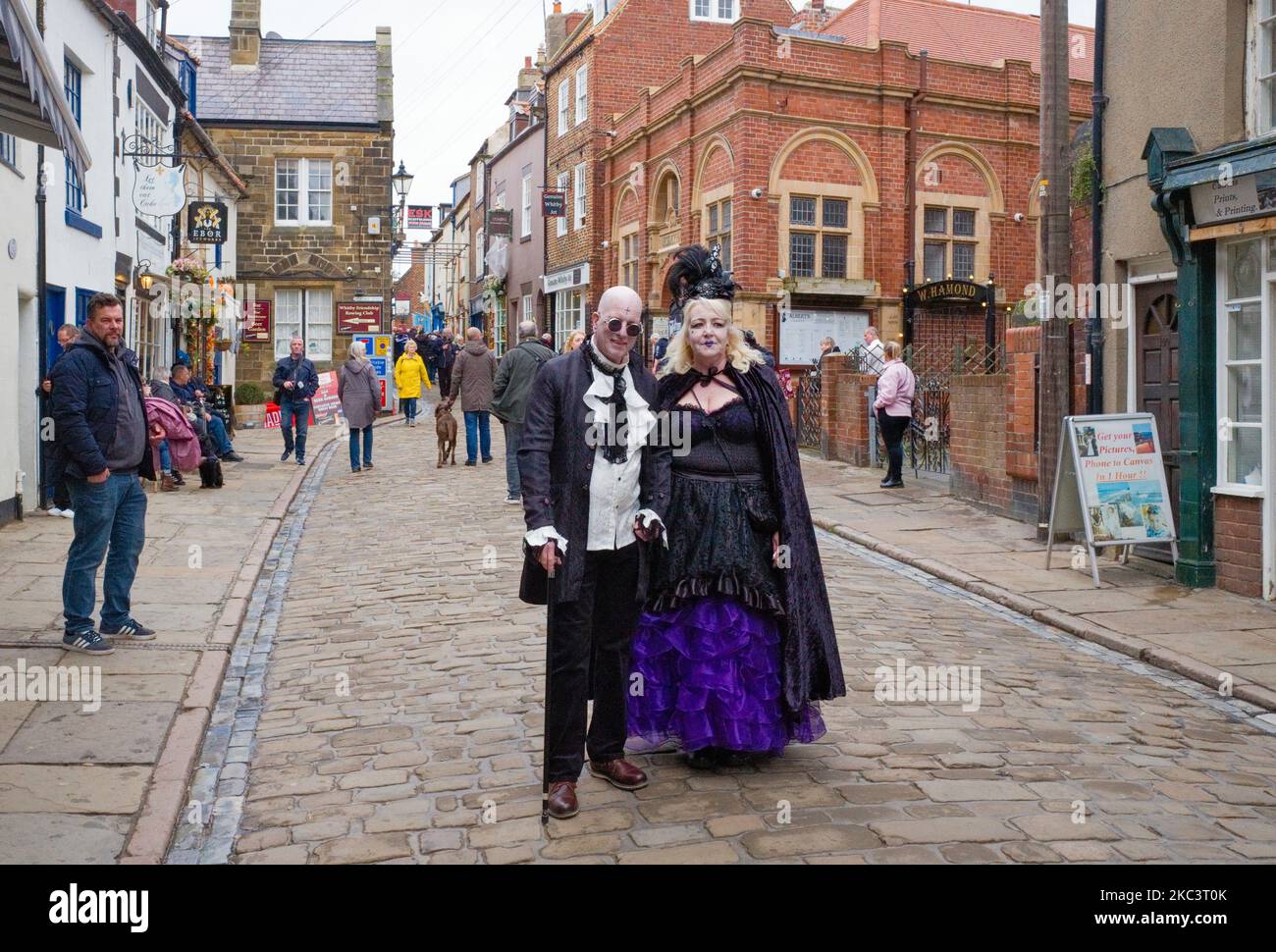A goth couple posing in Church Street, Whitby during goth weekend before the crowds fill the street Stock Photo