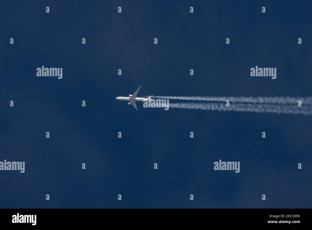 An Emirates Boeing 777 passenger aircraft flying in the blue sky at 39.000 ft from Dubai DXB International Airport in UAE to Manchester MAN in the UK flight no EK17. The overflying wide-body airplane Boeing B777-300 777-31H(ER) has the registration A6-EGV and is powered by 2x GE jet engines. Emirates is flying during the Covid-19 Coronavirus Pandemic with large wide-body planes. The overfly airliner creates contrail or chemtrail while cruising, forming a white line of condensation trail in the atmosphere behind it. Eindhoven, Netherlands on 11 November 2020 (Photo by Nicolas Economou/NurPhoto) Stock Photo