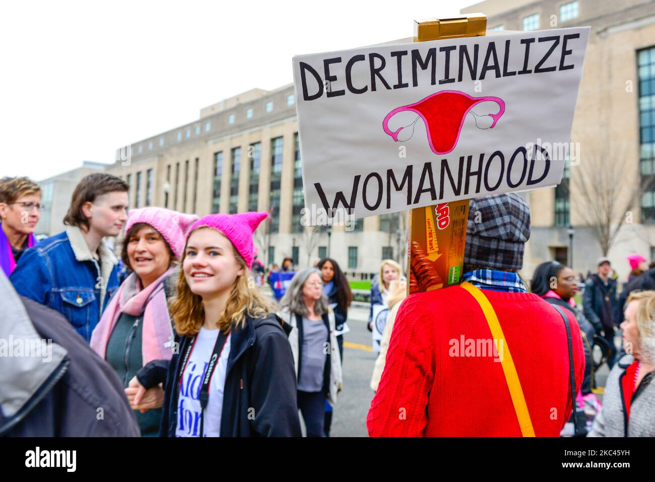 women with pink pussy hats, hold Poster holds sign that states 'Decriminalize womanhood', fight for Abortion rights, march on Washington DC Stock Photo