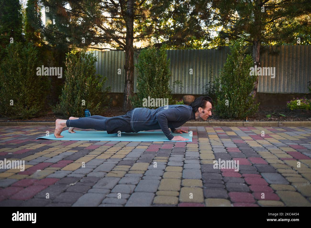 Side portrait of an active athlete man yogi, doing Yoga chaturanga push