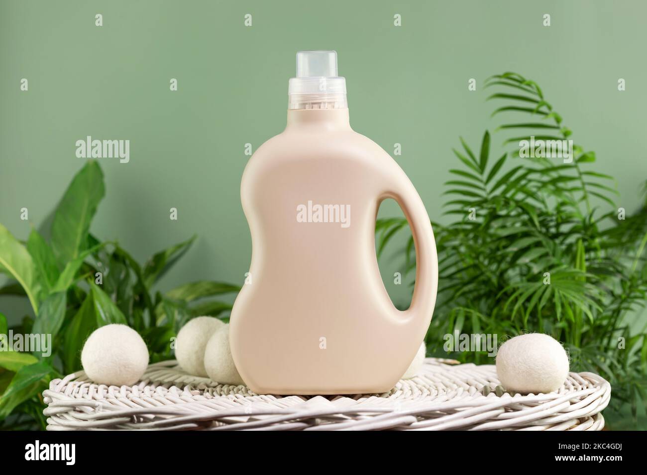 Natural laundry detergent mockup. Washing detergent concept with bottles of washing gel or fabric softener on a white laundry basket on a green backgr Stock Photo