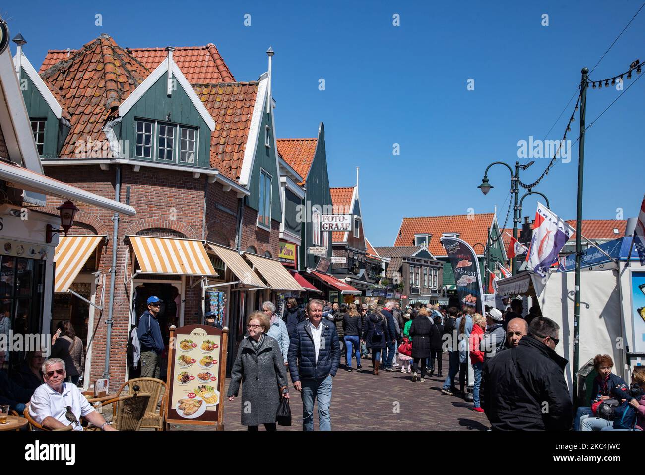 Daily life in Volendam traditional fishing village with Dutch architecture in North Holland near Amsterdam in The Netherlands. Volendam has a harbor and is a popular destination and tourist attraction in the country. There are old fishing boats, traditional clothing of locals, ferry ride to Marken, museums, cheese factroy, cafe and souvenir shops at the waterfront and a little beach. There are houses along the shore and a marina nearby for tourists and locals as visitors so tourism is the main income for the community. Volendam has been featured in many recent movies. Volendam - The Netherland Stock Photo