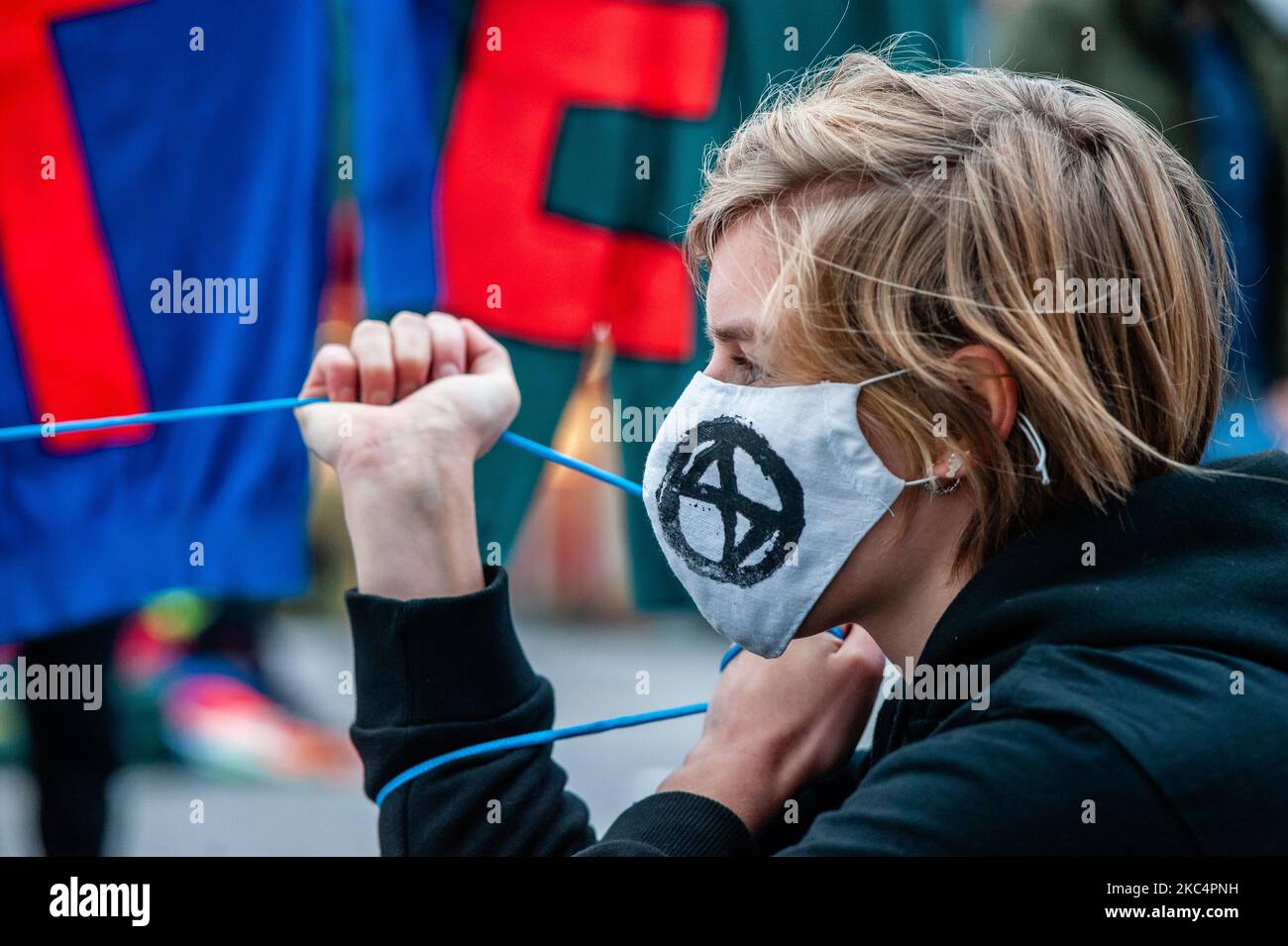 A climate activist is holding a banner while wearing a mask with the Extinction Rebellion logo on it, during the 'Circus protest' against Black Friday, in Utrecht, on November 27th, 2020. (Photo by Romy Arroyo Fernandez/NurPhoto) Stock Photo