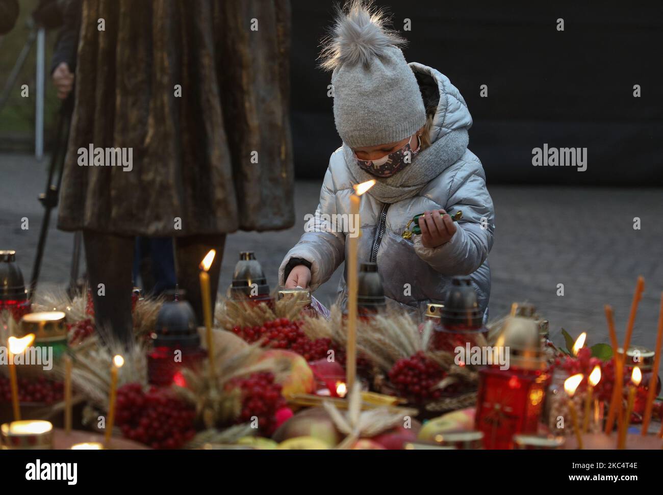 A girl lay a pair of candies as people lit candles and lay bouquets from ears ang arrowwood to the memorial of Great Famine victims during mourning rally in Kyiv, Ukraine, November 28, 2020.Ukraine honors the memory of the victims of the famines and Great Famine (Holodomor) of 1932 – 1933 when 4.5 million Ukrainians, including 600,000 unborn children, were starved to death by the Soviet regime under Joseph Stalin. (Photo by Sergii Kharchenko/NurPhoto) Stock Photo