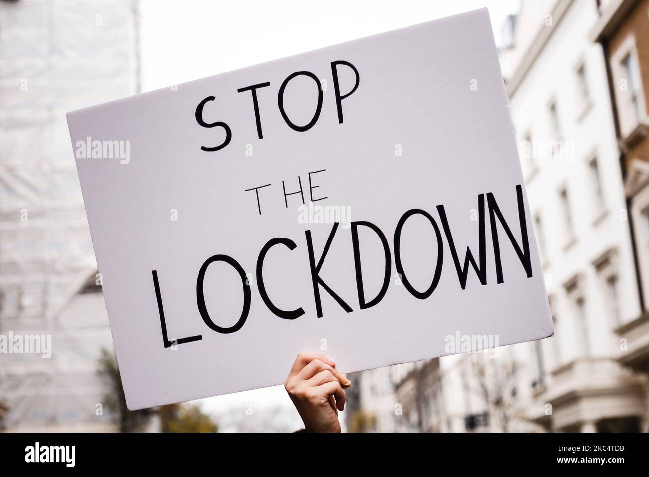 An anti-lockdown activist holds up a 'Stop The Lockdown' placard during a demonstration in London, England, on November 28, 2020. In an evening update the Metropolitan Police announced it had made 155 arrests over the course of the day's demonstrations, for offences including breaches of coronavirus regulations, assault on police and possession of drugs. London is to return to 'Tier 2' or 'high alert' covid-19 restrictions once the current England-wide coronavirus lockdown ends next Wednesday. All three of the tiers, assigned to local authorities across England, have been strengthened since th Stock Photo