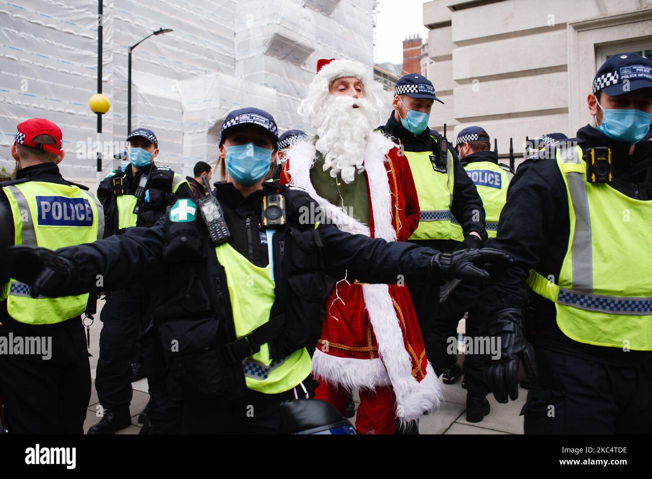 An anti-lockdown activist dressed as Father Christmas is arrested in Grosvenor Square during a demonstration in London, England, on November 28, 2020. In an evening update the Metropolitan Police announced it had made 155 arrests over the course of the day's demonstrations, for offences including breaches of coronavirus regulations, assault on police and possession of drugs. London is to return to 'Tier 2' or 'high alert' covid-19 restrictions once the current England-wide coronavirus lockdown ends next Wednesday. All three of the tiers, assigned to local authorities across England, have been  Stock Photo