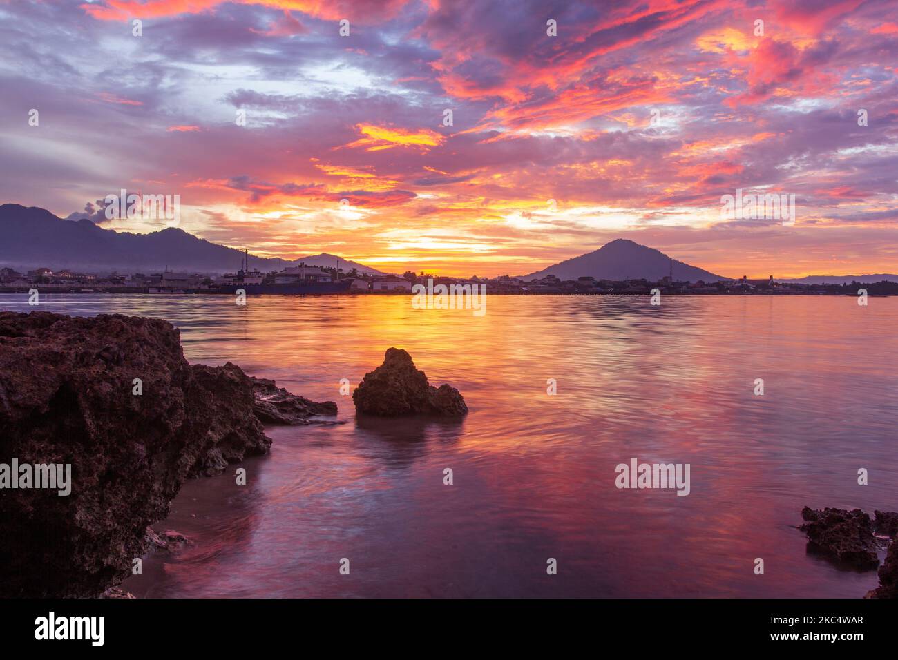 Landscape with rocks, beaches, reddish sky at dusk and small islands in ...