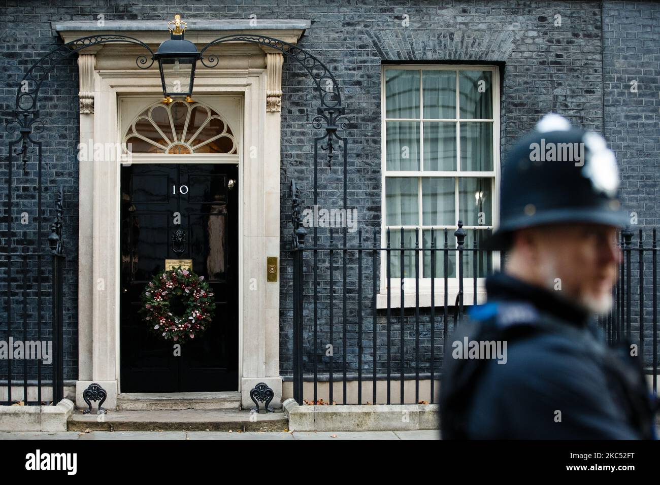 A police officer stands guard outside the door of 10 Downing Street, on which now hangs a Christmas wreath for the festive season, in London, England, on December 1, 2020. (Photo by David Cliff/NurPhoto) Stock Photo
