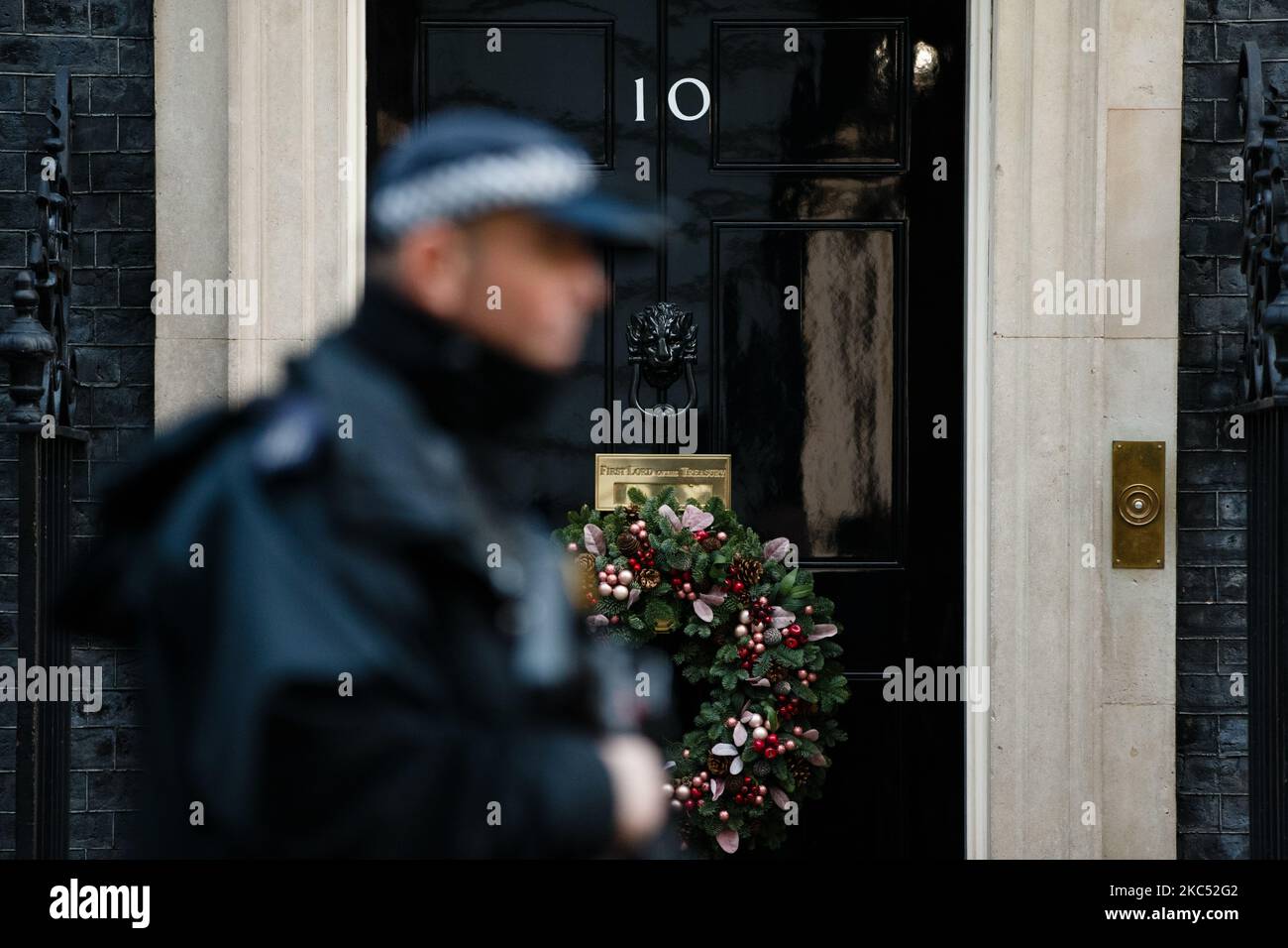 A police officer passes the door of 10 Downing Street, on which now hangs a Christmas wreath for the festive season, in London, England, on December 1, 2020. (Photo by David Cliff/NurPhoto) Stock Photo