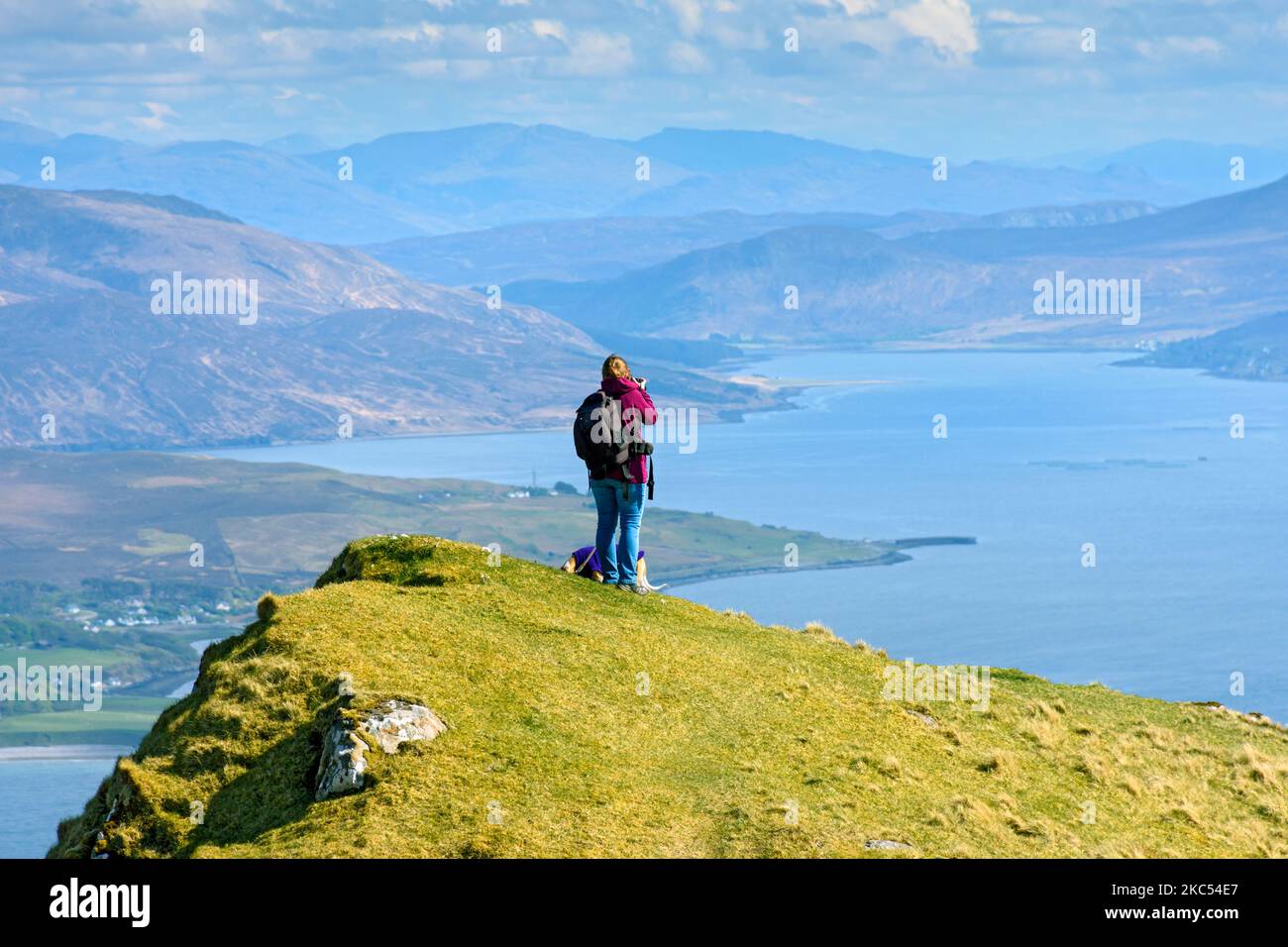 A walker on the summit ridge of Ben Tianavaig admiring the view over the Inner Sound towards the mainland.  Near Portree, Isle of Skye, Scotland, UK Stock Photo