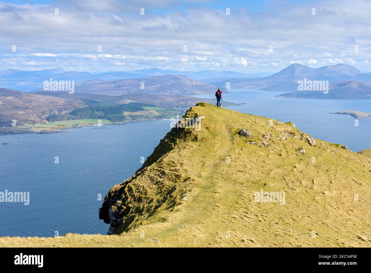 A walker on the summit ridge of Ben Tianavaig looking over the Inner Sound to the Red Cuillin hills.  Near Portree, Isle of Skye, Scotland, UK Stock Photo