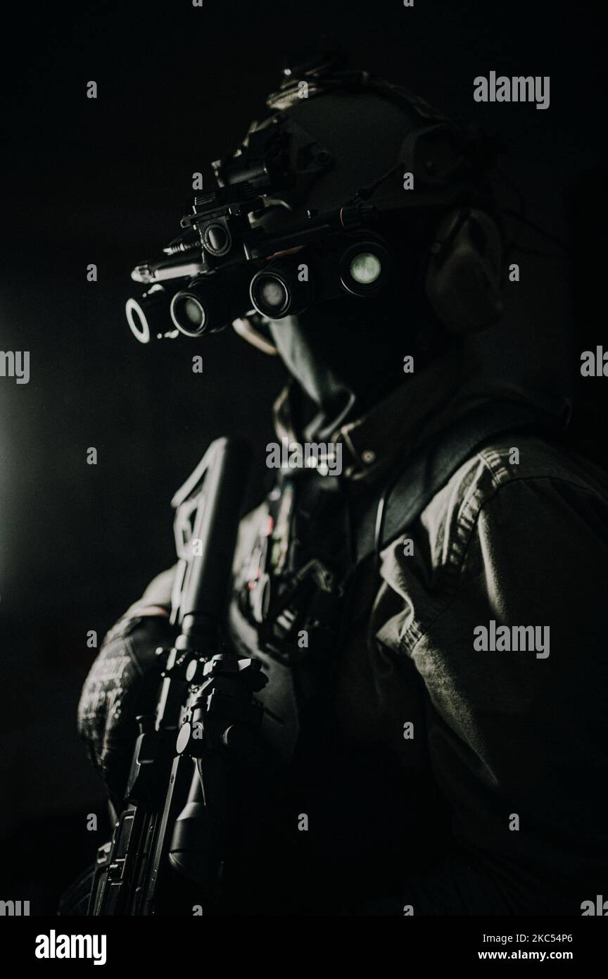 A vertical shot of soldier with gun wearing night vision goggles Stock Photo