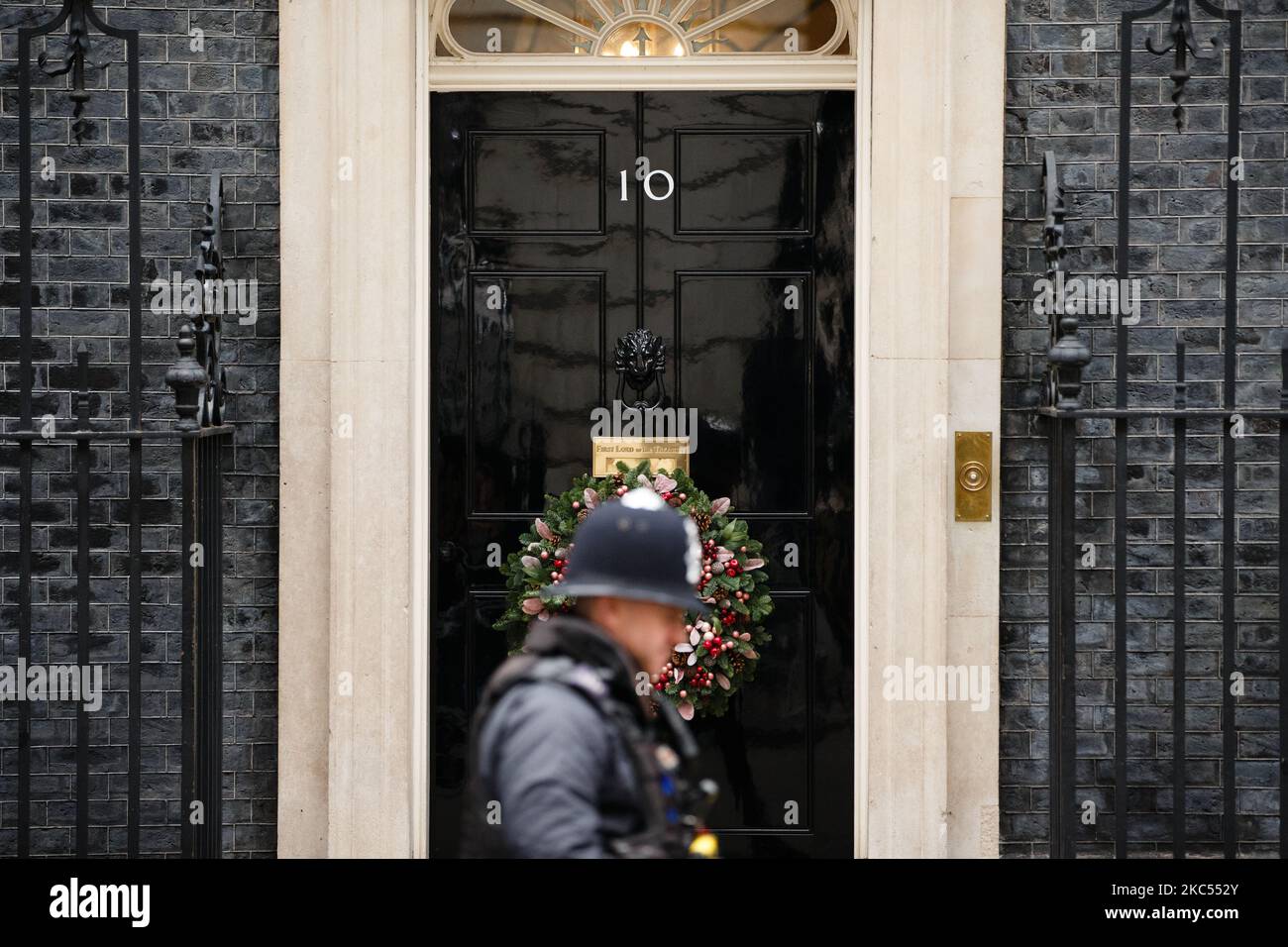 A police officer walks past the door of 10 Downing Street, on which now hangs a Christmas wreath for the festive season, in London, England, on December 2, 2020. (Photo by David Cliff/NurPhoto) Stock Photo