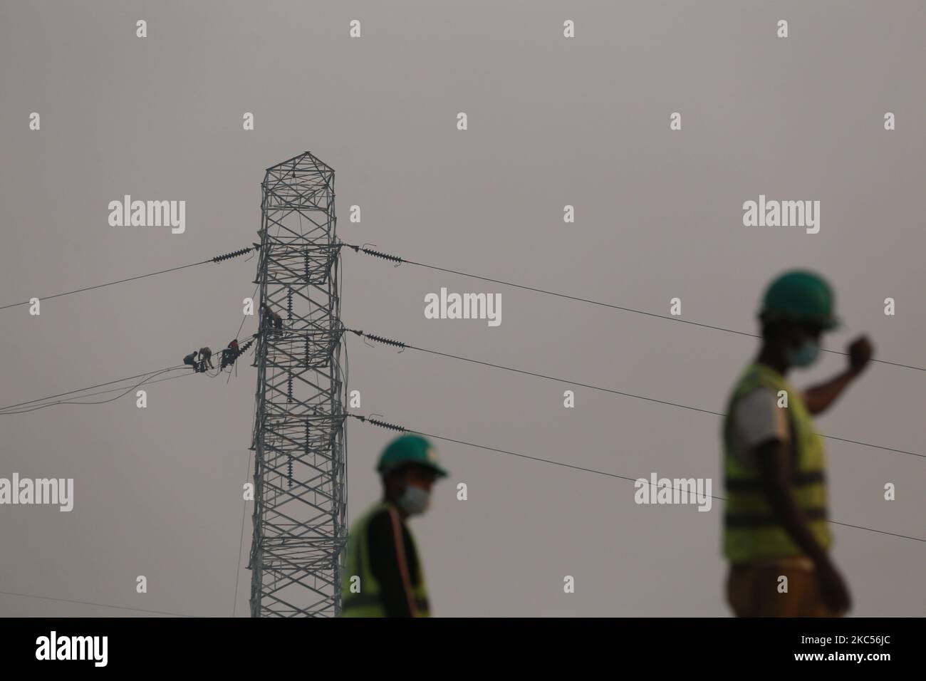 Workers assemble electricity installations in high voltage towers at an