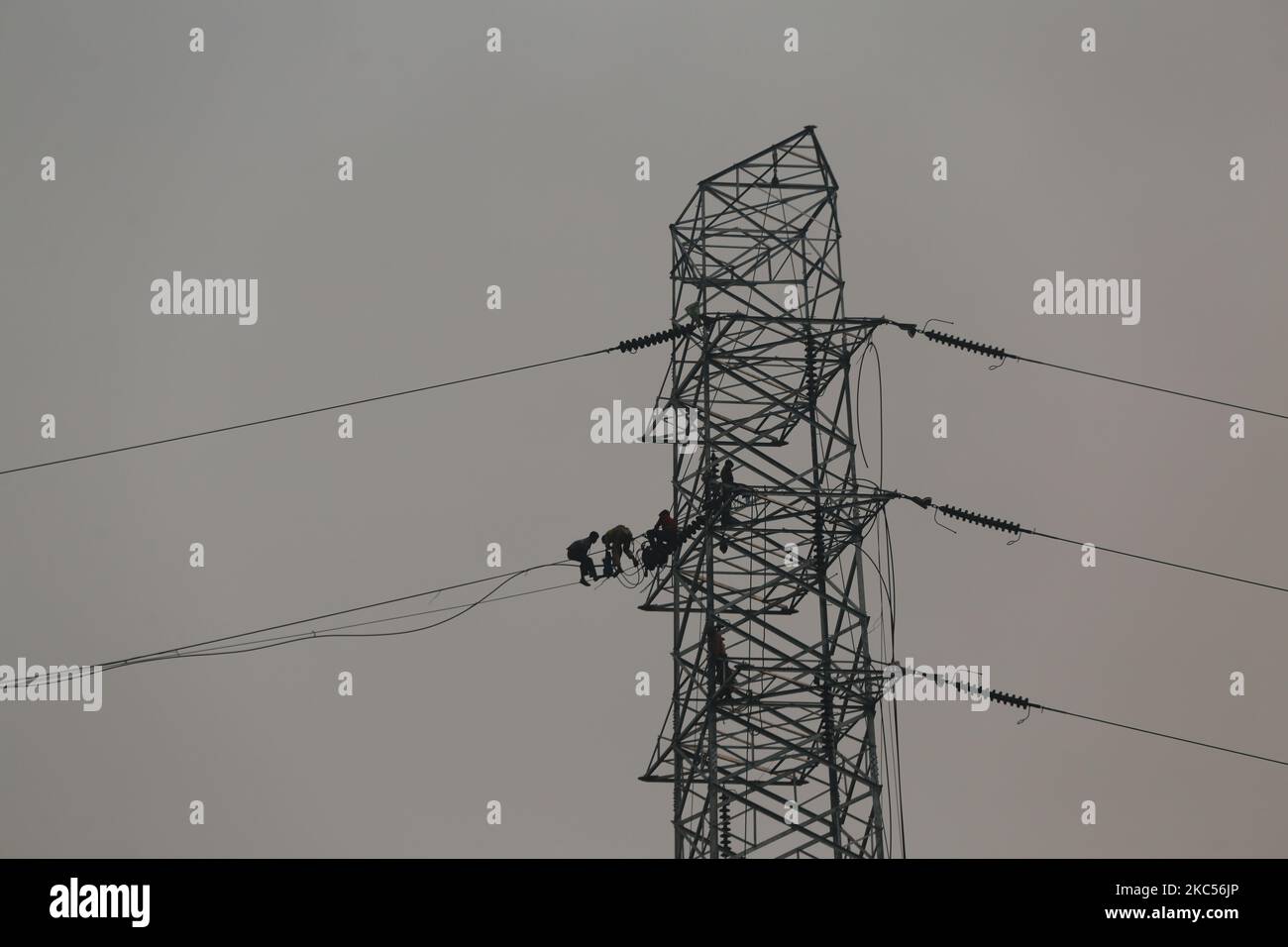 Workers assemble electricity installations in high voltage towers at an
