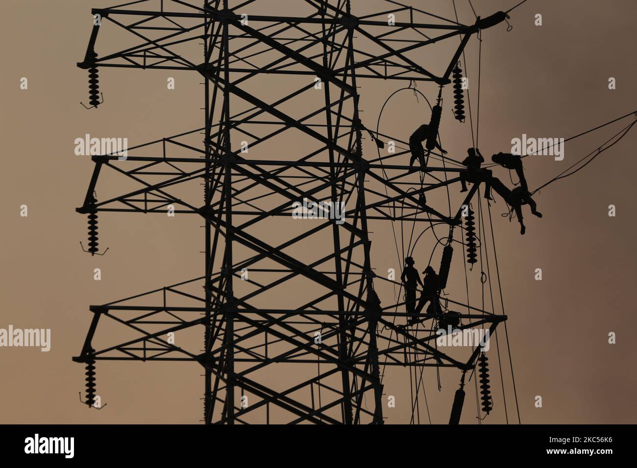 Workers assemble electricity installations in high voltage towers at an