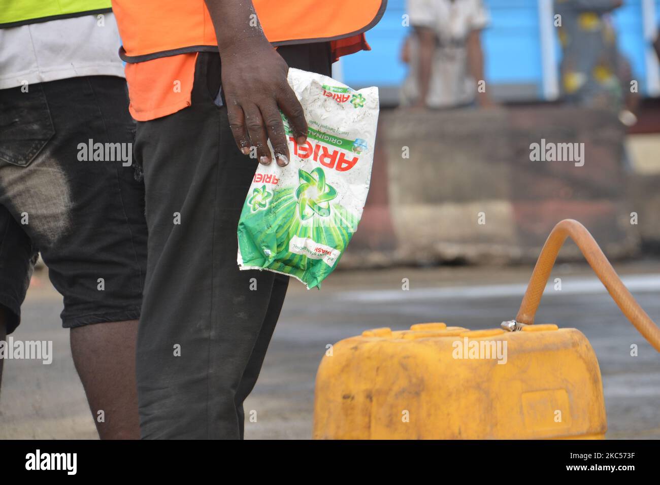 A man hold a sachet of detergent used to put out a tanker loaded with