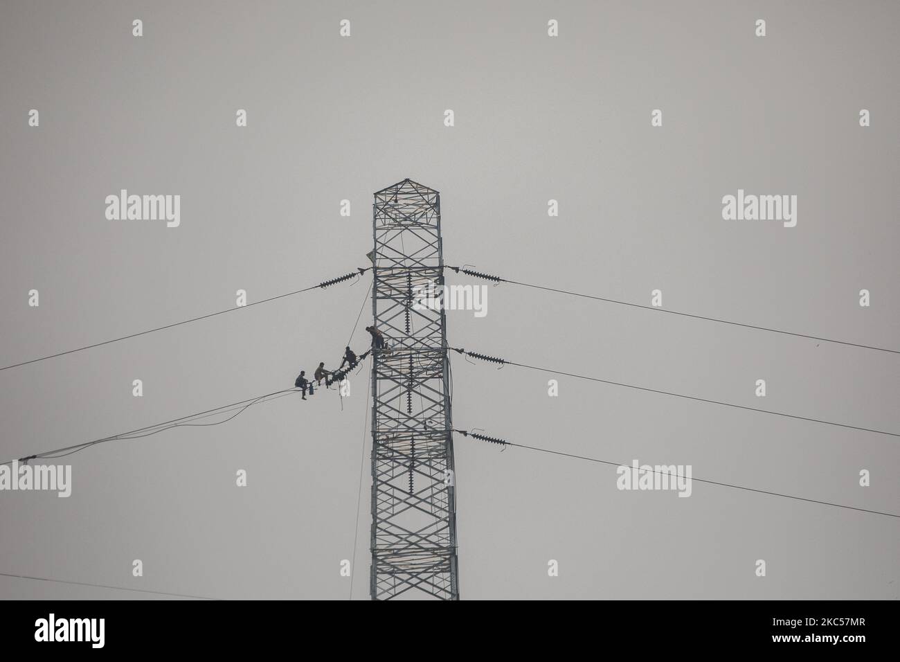 Workers assemble electricity installations in high voltage towers at an