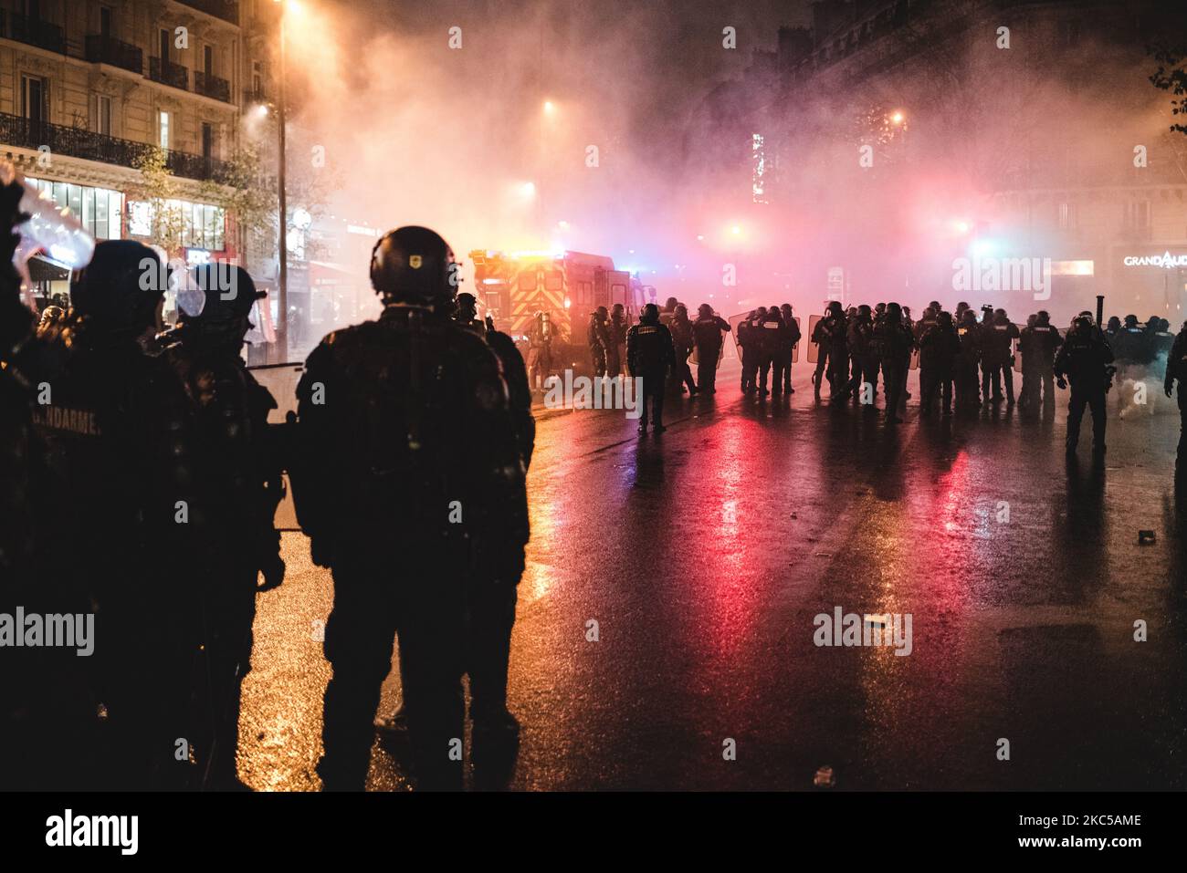 Anti-riot police officers accompanied by firefighters who came to put out the beginning of the fires are trying to disperse the numerous demonstrators who gathered in the early evening on the Place de la République on December 5, 2020, when the third day of mobilization against the so-called 'Global Security' bill was taking place in France. In Paris several thousand demonstrators gathered at Porte de Lilas to protest against article 24 prohibiting the dissemination of police images on social networks and article 23 on the use of drones by the police and facial recognition. Quickly Black Bloc  Stock Photo
