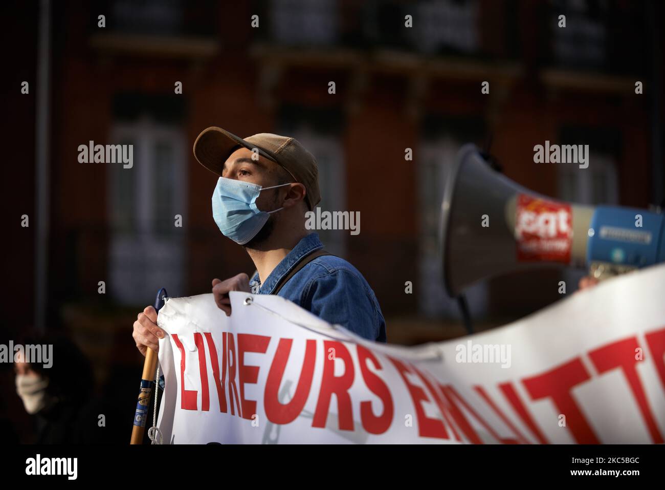 A delivery man holds a banner against their bad conditions of work