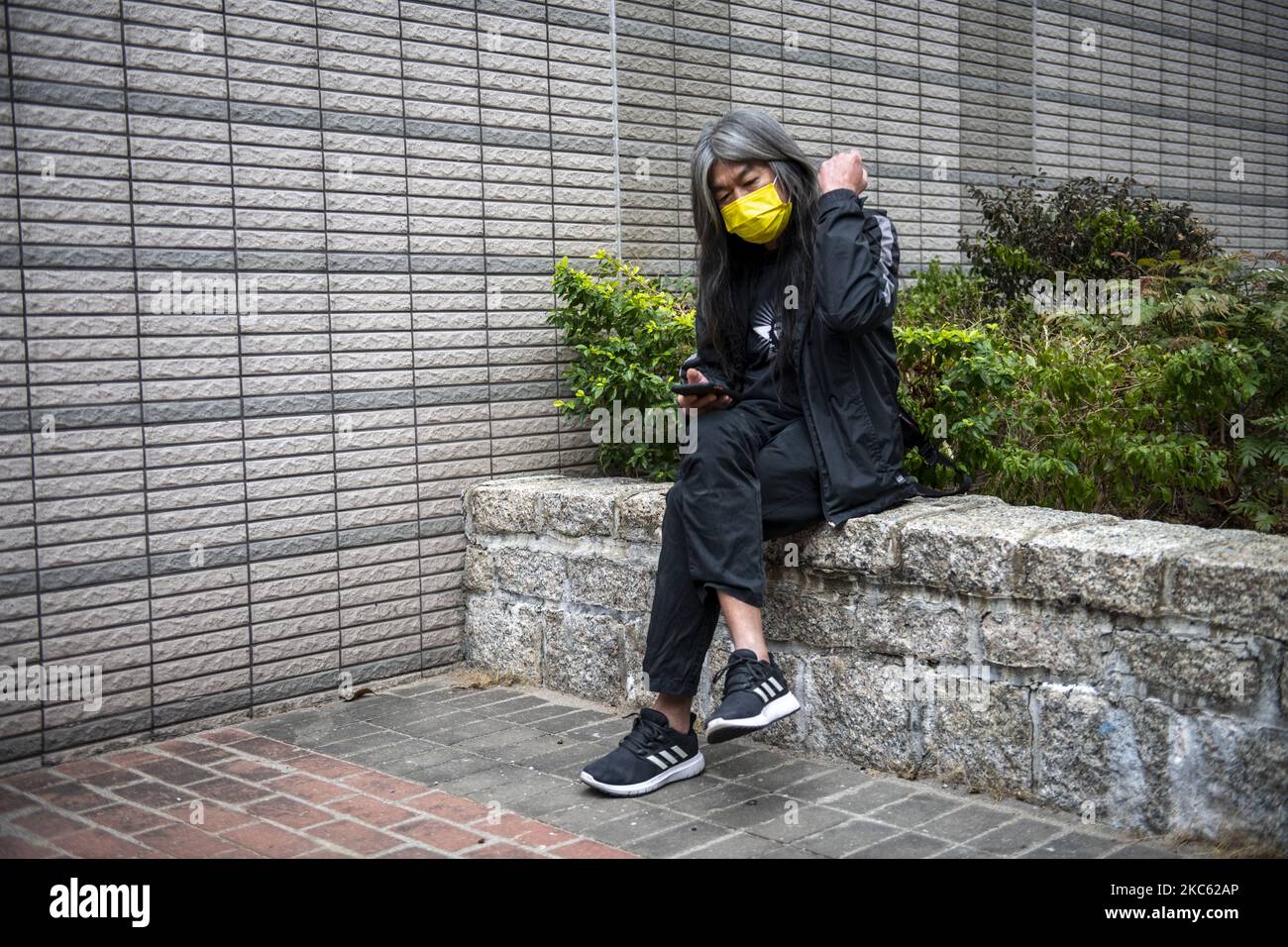 â€œLong Hairâ€ Leung Kwok-hung wearing a yellow face mask is seen fixing his hair as he sits outside the West Migrants Court on December 17, 2020 in Hong Kong, China. Leung Kowk-Hung , Figo Chan, Tsang Kin-Shing , former lawmaker Eddie Chu and Wu Chi-wai are all charge with crimes related to the Anti-National Security Protest on July 1, 2020 . (Photo by Vernon Yuen/NurPhoto) Stock Photo