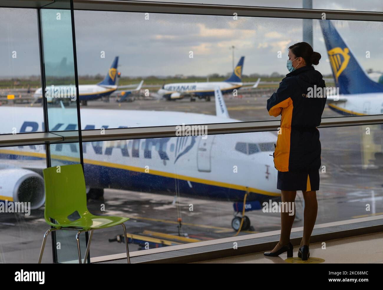A member of Ryanair cabin crew looks out of the window at Ryanair planes grounded at Dublin Airport (file picture December 5). From midnight all flights and passenger ferries from Britain to Ireland will be suspended for an initial period of 48 hours in an effort to stop the spread of a new coronavirus strain to Ireland. On Sunday, December 20, 2020, in Dublin, Ireland. (Photo by Artur Widak/NurPhoto) Stock Photo