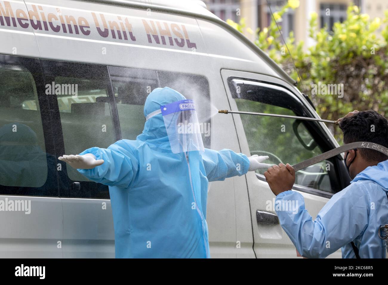 Sri Lankan health workers dressed in protective suits are sprayed with
