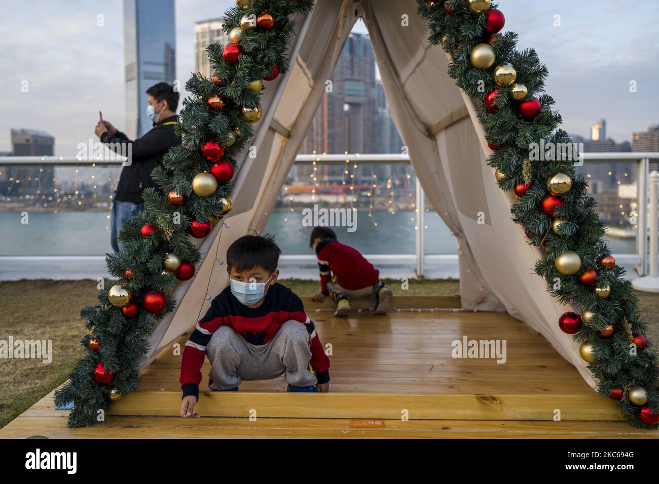 A boy wearying a faec Mask is seen sitting inside a tent at a Christmas display in a shopping mall on December 21, 2020 in Hong Kong, China. Hong Kong has banned flights from the United Kingdom in response to a new variant of Covid-19 discovered there, the new variant is believed to be 70% more transmissible, Hong Kong has also extend its social distancing measure till January 6 next year. (Photo by Vernon Yuen/NurPhoto) Stock Photo