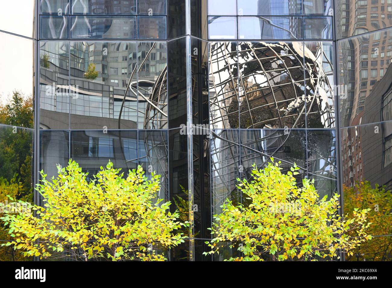 NEW YORK - 23 OCT 2022: The Steel Globe at Columbus Circle reflection in the side of the Trump International Hotel and Tower, with trees in fall folia Stock Photo