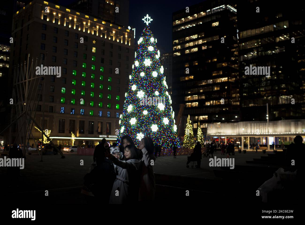 A group of people posing in front of the giant Christmas tree set up in