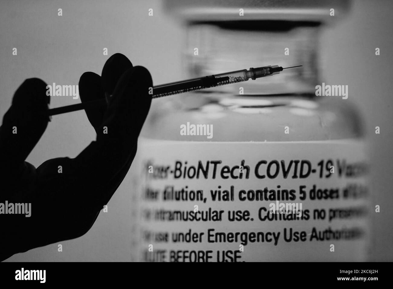 An illustrative image of a medical syringe in front of an image of a vial containing Pfizer-BionTech vaccine displayed on screens. On Monday, December 28, 2020, in Dublin, Ireland. (Photo by Artur Widak/NurPhoto) Stock Photo