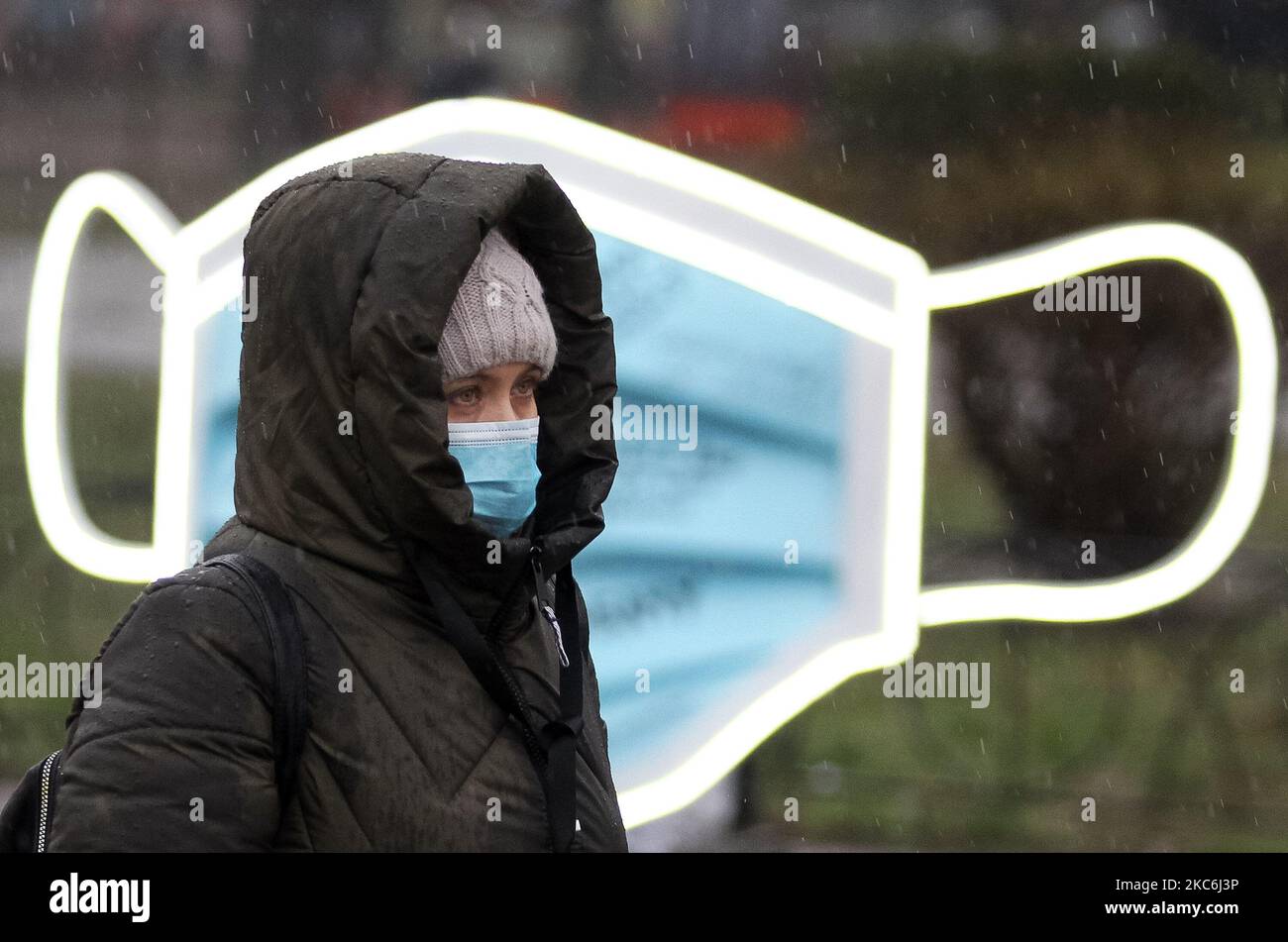 A woman wearing a protective face mask amid the COVID-19 coronavirus epidemic walks next to an art-object of the largest medical mask in Ukraine during an event on Kontraktova Square in the center of Kyiv, Ukraine on 28 December 2020. The event named 'Cover yourself with a mask, not inside yourself' is a part of the social campaign aimed to draw attention to mental health problems during the Covid-19 coronavirus pandemic, as local media reported. The mask letterings like: 'If only not to get sick',' I'm afraid for my parents',' Will I really lose my job?','When will I see my grandchildren?', ' Stock Photo