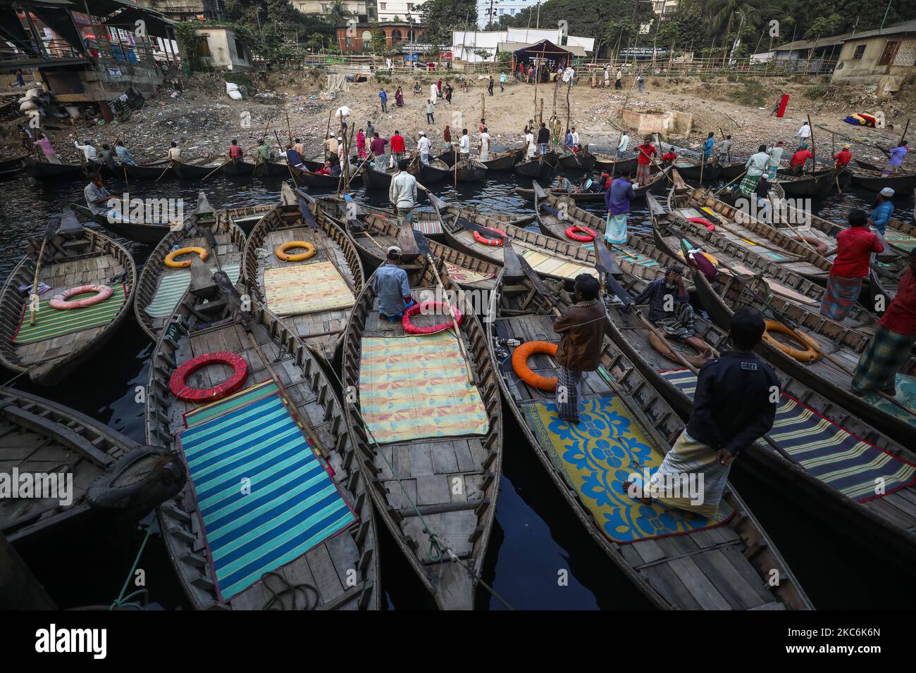 Boatmen load passengers on their boats to take them across the River Buriganga at the Sadarghat terminal in Dhaka on December 29, 2020.The Buriganga is economically a very important river for the capital. Launches and boats connect the capital to other parts of this riverine country through the Buriganga. (Photo by Ahmed Salahuddin/NurPhoto) Stock Photo