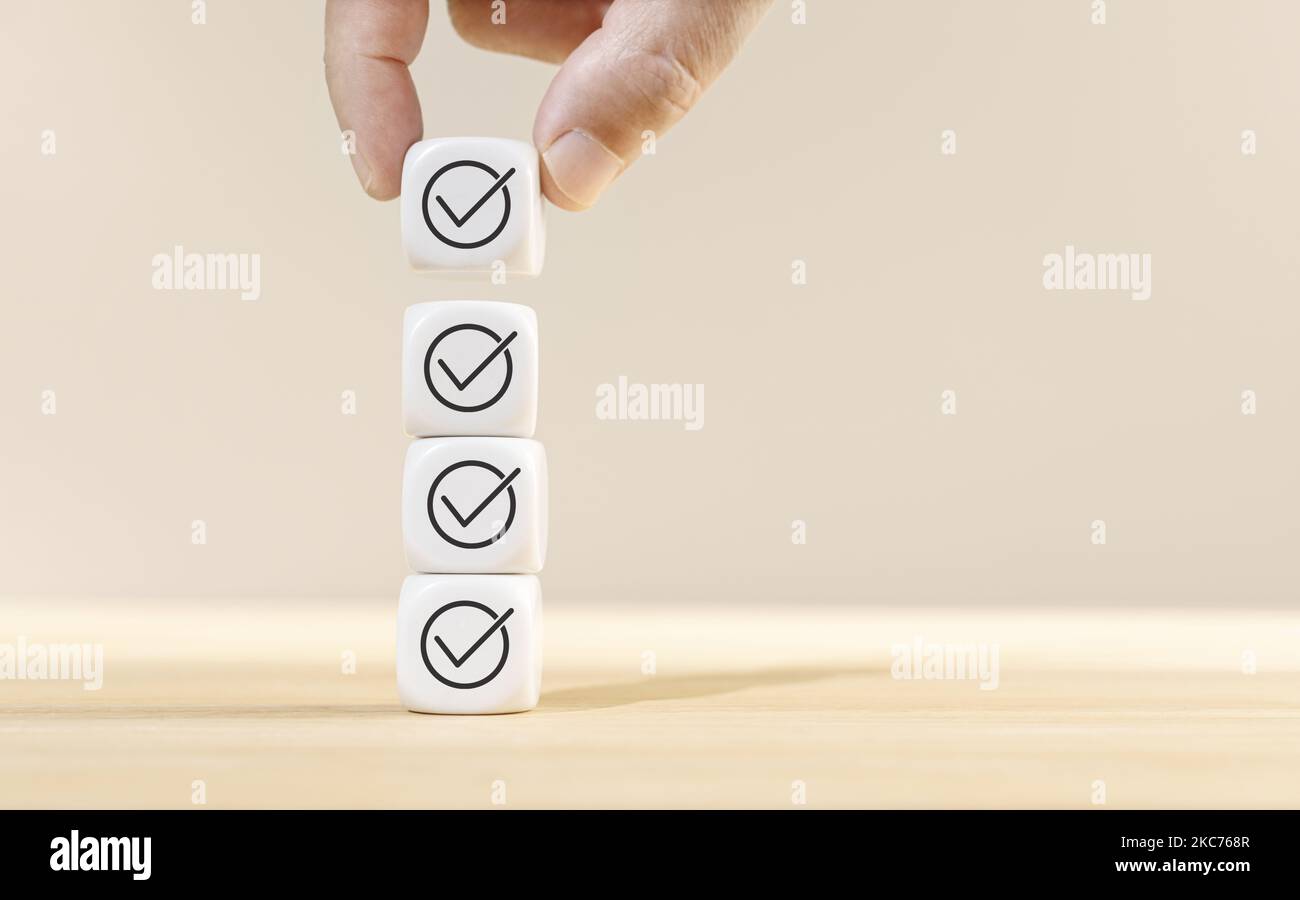 Hand holding a cube block on top of other blocks stacked with check ...