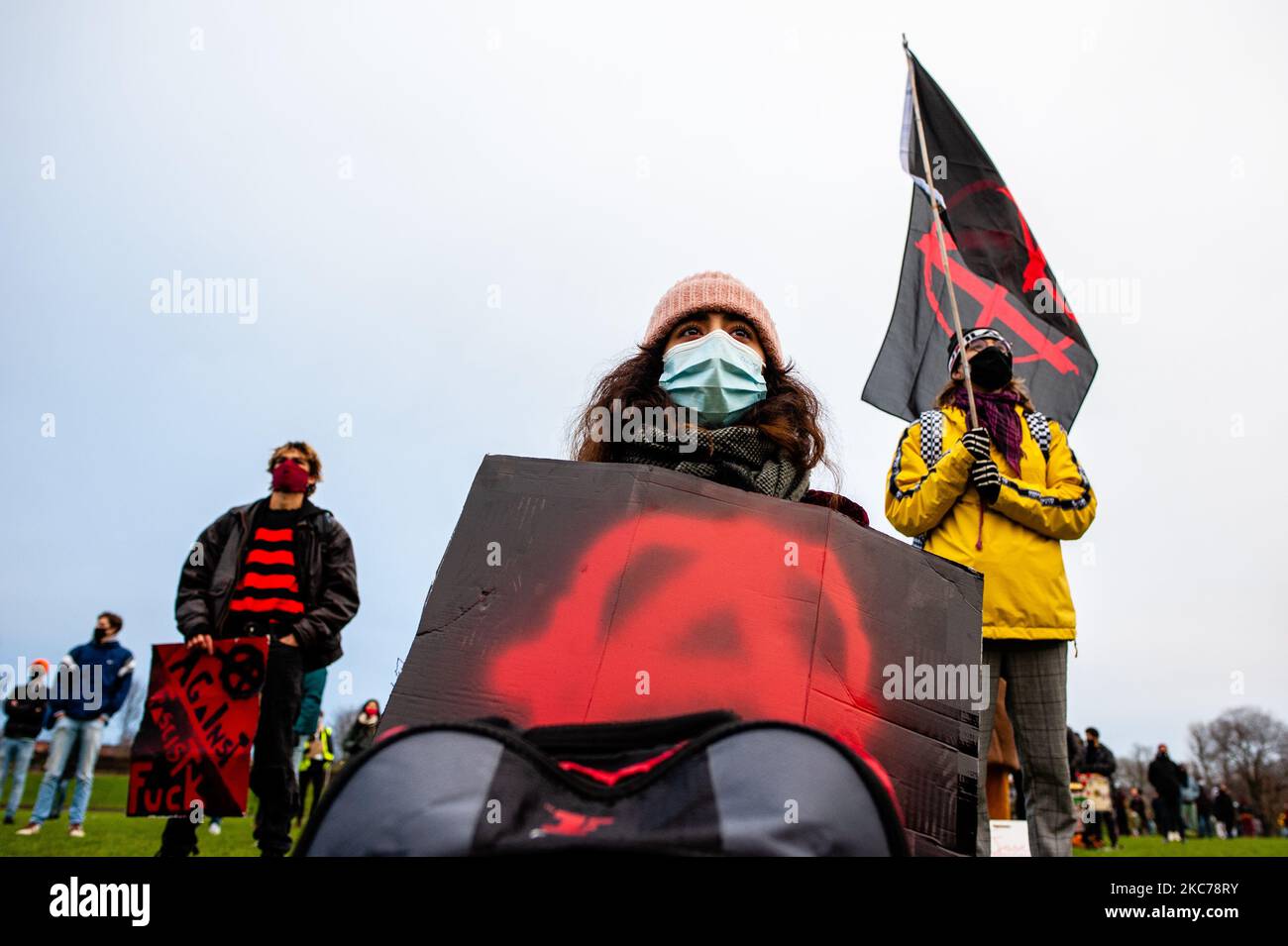 A woman is sitting on the floor while holding an Anarchist placard, during a demonstration against fascism in Amsterdam, Netherlands on January 10th, 2021. After the 'attempted coup' at the US Capitol building that left five people dead, several organizations in Amsterdam organized a demonstration against fascism. Hundreds of people gathered at the Westerpark to protest against the rise of the far-right movement in Europe and in the USA. (Photo by Romy Arroyo Fernandez/NurPhoto) Stock Photo