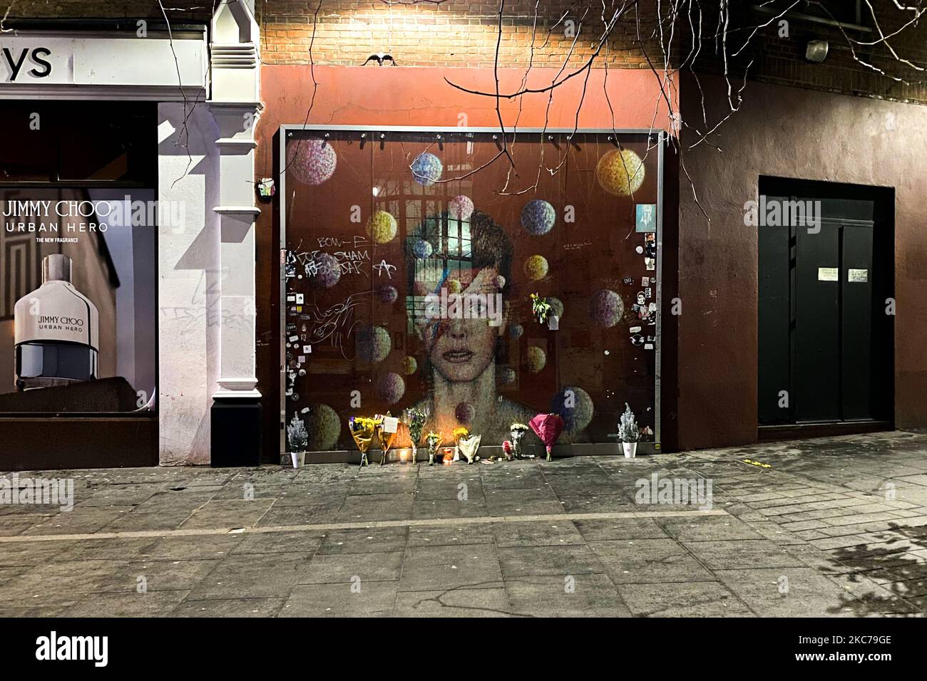 Flowers and candles are left past a mural depicting the cover of Aladdin Sane, to remember the firth anniversary of the death of the British iconic musician David Bowie, in Brixton, south London on January 10, 2021. David Bowie died just two days after his birthday and the relase of his last album, 'Blackstar'. (Photo by Alberto Pezzali/NurPhoto) Stock Photo