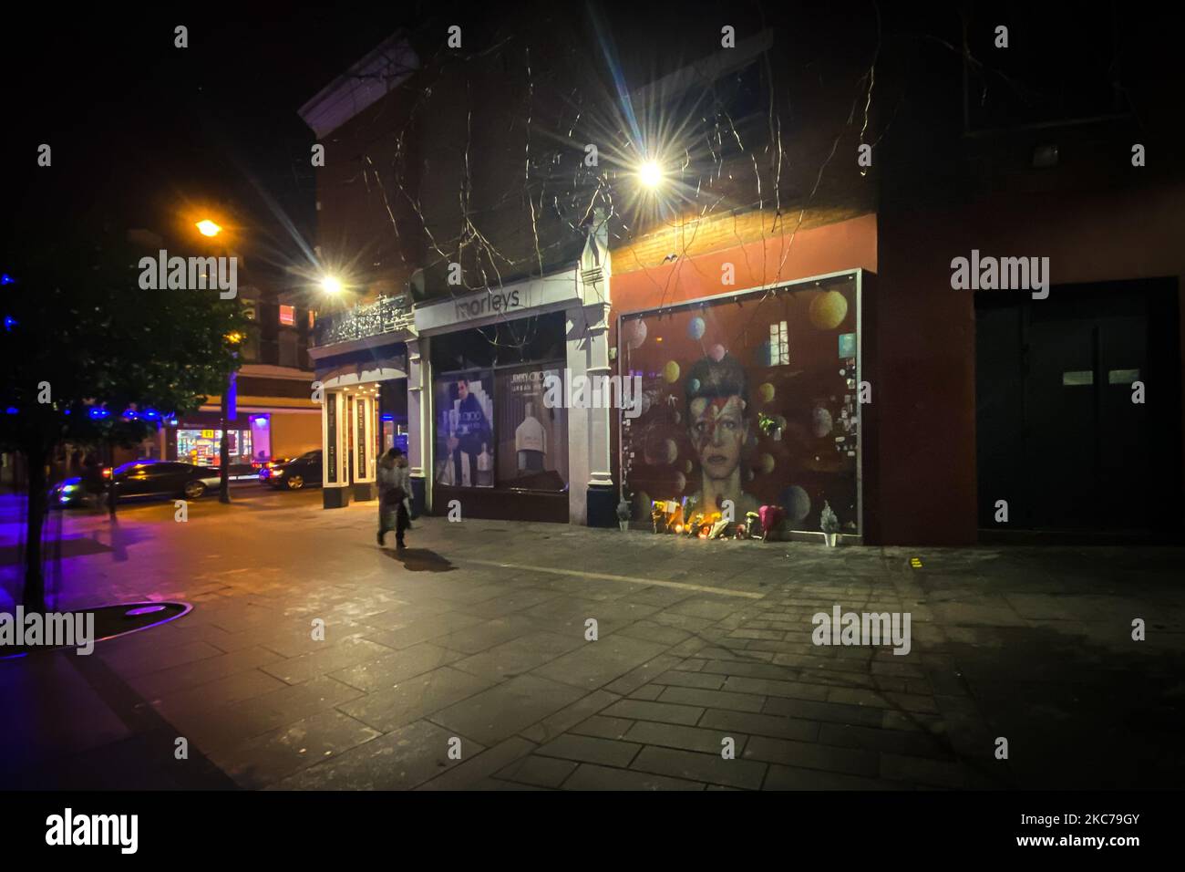 Flowers and candles are left past a mural depicting the cover of Aladdin Sane, to remember the firth anniversary of the death of the British iconic musician David Bowie, in Brixton, south London on January 10, 2021. David Bowie died just two days after his birthday and the relase of his last album, 'Blackstar'. (Photo by Alberto Pezzali/NurPhoto) Stock Photo